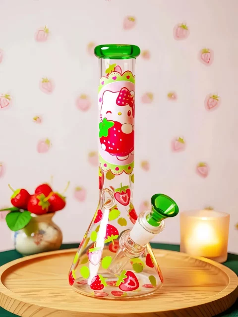 Hello Kitty strawberry beaker bong with green accents and clear glass. Fresh garden design, sweet summer vibes, smooth hits for Sanrio fans.