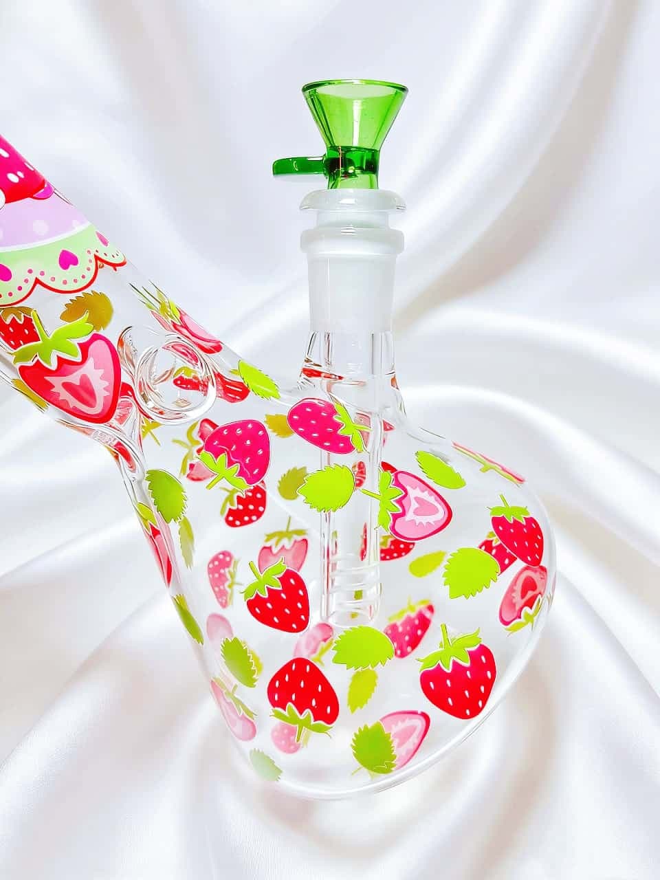 Hello Kitty strawberry beaker bong with green accents and clear glass. Fresh garden design, sweet summer vibes, smooth hits for Sanrio fans.